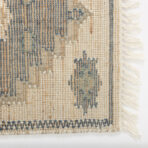 Close up of a woven beige and blue striped rug with fringe along the edge