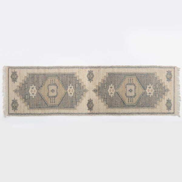 Top-down view of a vintage beige rug with blue geometric diamonds and fringed edges on a white background.