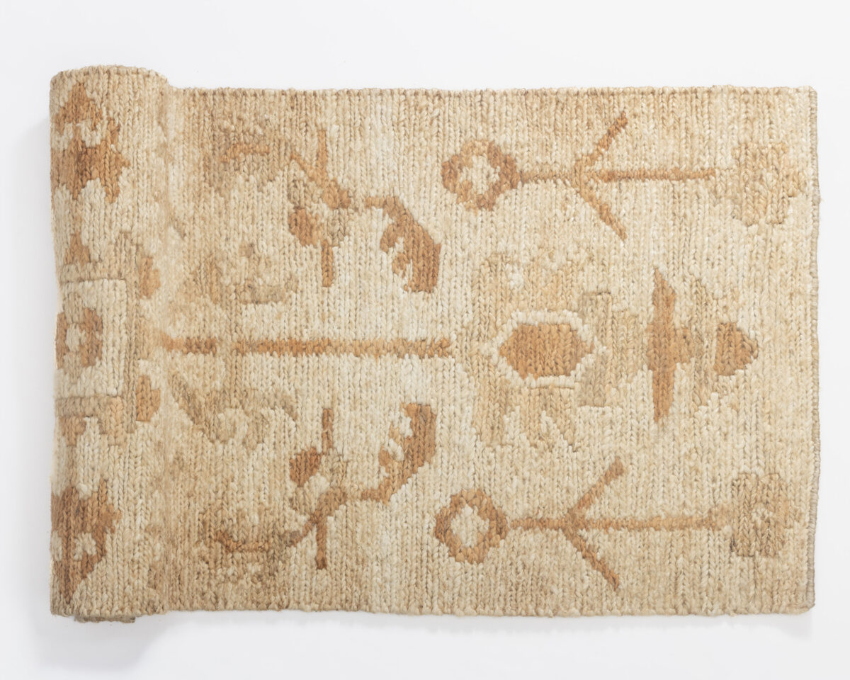 Close up of a beige woven rug with a subtle tan geometric pattern