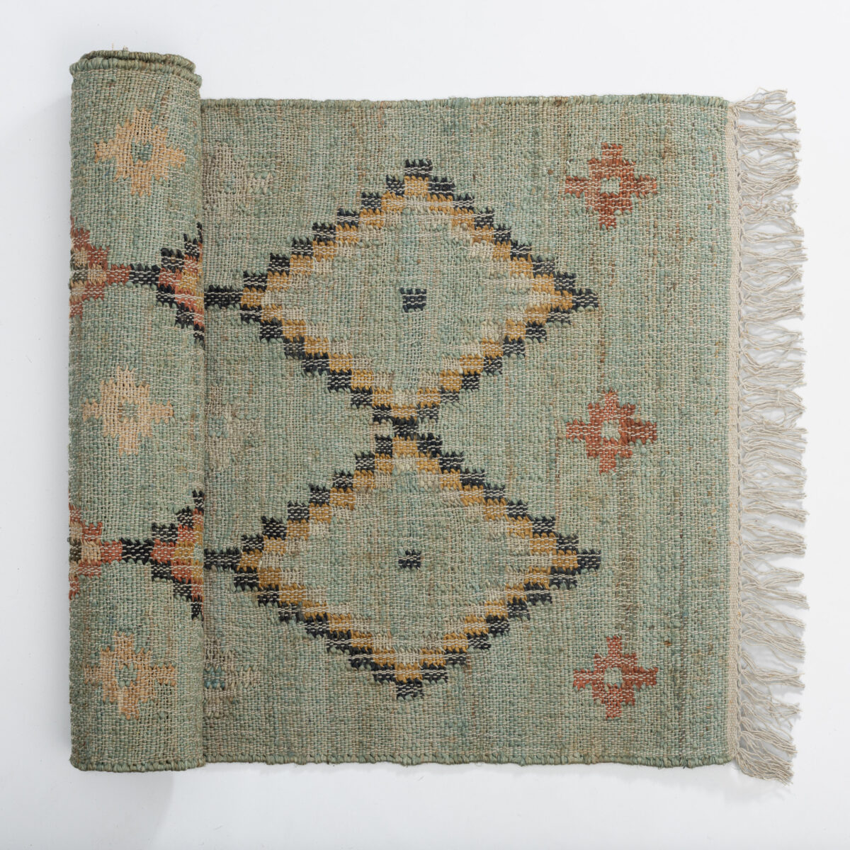 Teal woven rug with geometric diamond and zigzag patterns in yellow ivory and black fringed along the right edge
