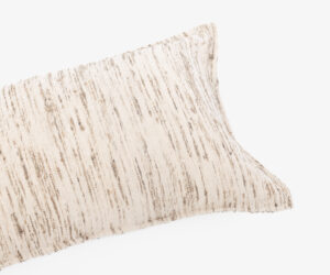 Close up of a beige striped fabric edge against a white background showing textured weave typical of a cushion cover