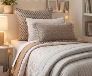 Cozy bed with patterned pillows and striped quilt string lights plant and books on a shelf in soft warm lighting