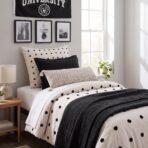 Bedroom with black and white decor polka dot pillows and bedding black framed art on the wall and a wooden nightstand by a sunny window