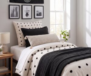 Bedroom with black and white decor polka dot pillows and bedding black framed art on the wall and a wooden nightstand by a sunny window