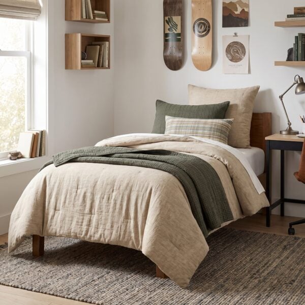 Bedroom with beige duvet green pillows wooden bed frame and a textured rug wall shelves hold books nearby