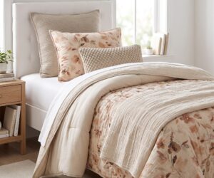 Cozy bedroom bed setup with a floral throw pillow and a textured beige cushion near a sunlit window