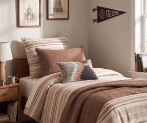 A cozy bedroom corner with a bed striped beige and brown bedding and matching pillows
