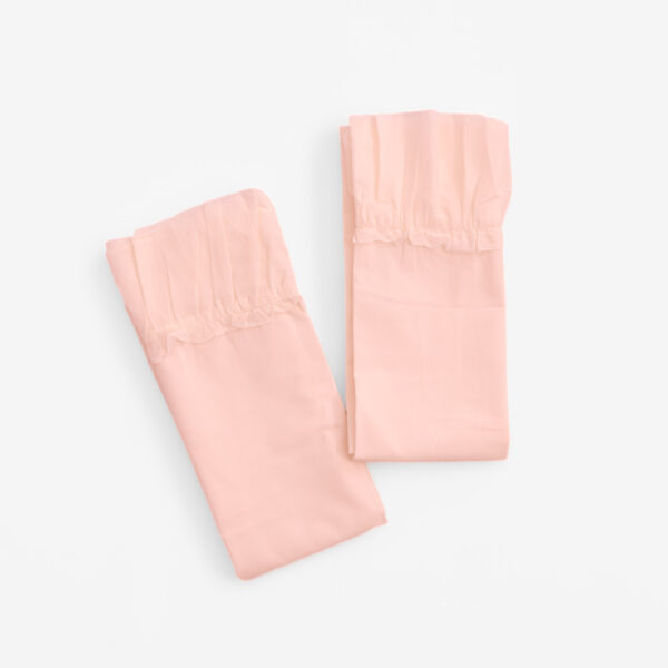 Three pale pink fabric pieces with gathered hems laid on a white background diagonally arranged