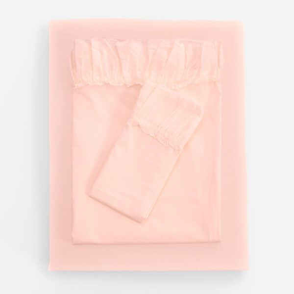 Soft pink blanket neatly folded on a pale pink bed creating a minimalist monochrome look