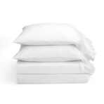 Three white pillows stacked on a white background creating a soft minimalist display