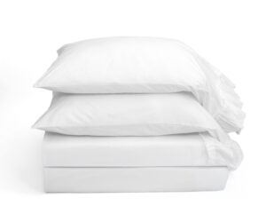 Three white pillows stacked on a white background creating a soft minimalist display
