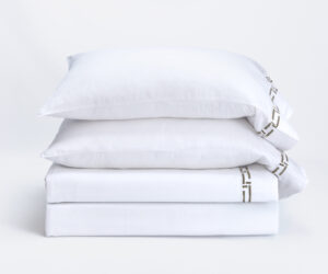 Three white pillows stacked on a white surface against a plain white background soft and clean look