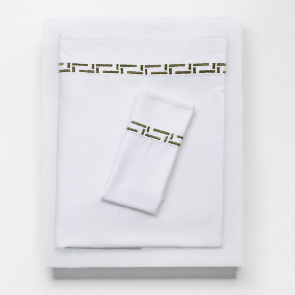 White folded linens with a beige green embroidered band along the edge decorative textile detail visible on top sheet and pillowcase border