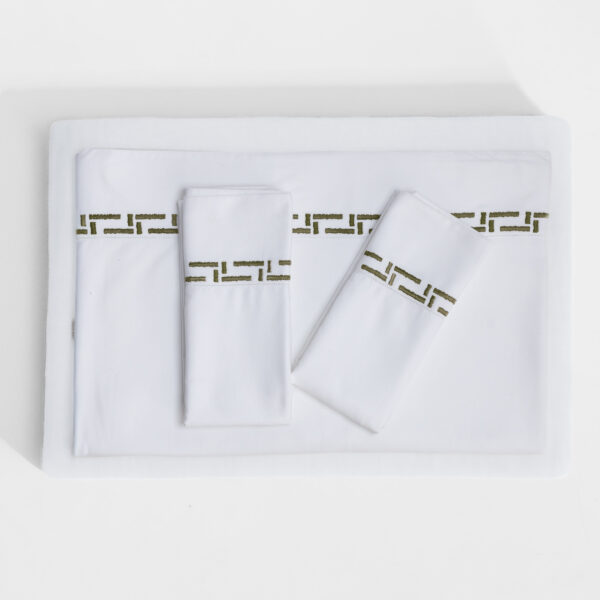 Top down view of a neatly made white bed with a decorative green geometric border on the pillowcase and sheet edges