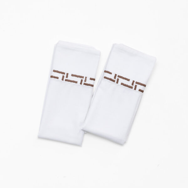 Close up of white fabric pieces with brown stitched details on a white background