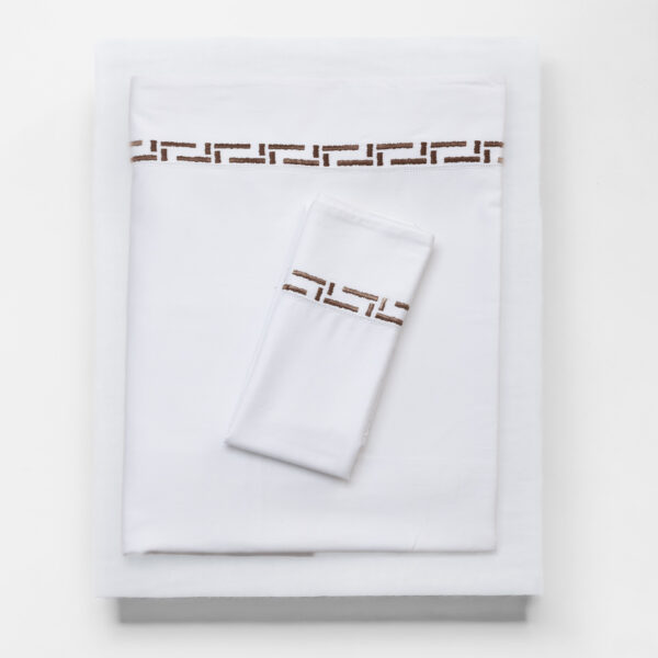 White folded linens with a brown geometric border along the edge close up