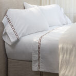 White pillows with brown geometric border on a beige headboardbed setting