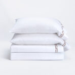 Stack of white pillows stacked on a white bed with a clean minimal look