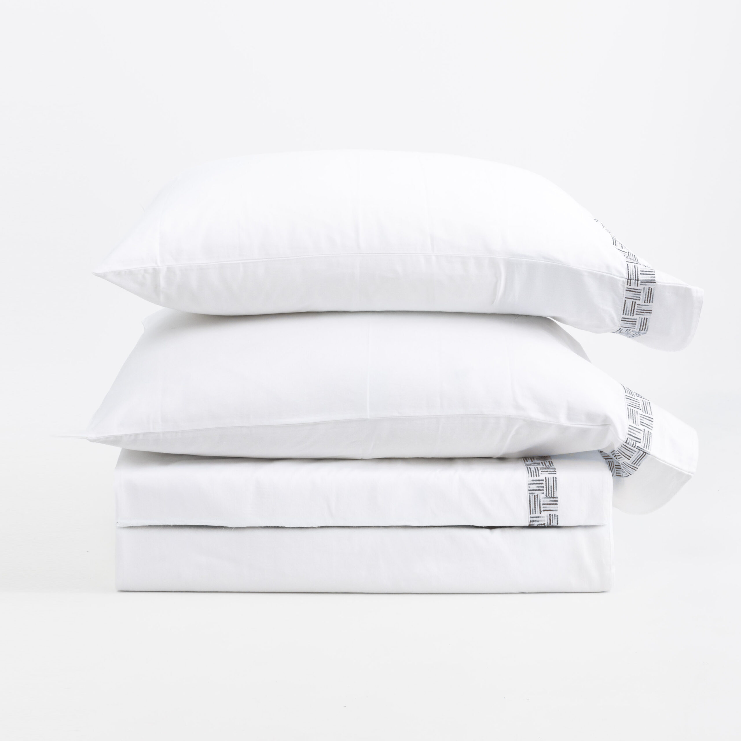 17217t 2 | Amity Home Stack of white pillows with a woven patterned edge on the right set against a white background product photo