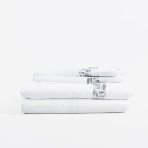 Stack of clean white towels folded neatly with a patterned newspaper print edge on a white surface