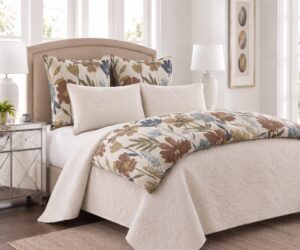 Beige upholstered bed with floral patterned pillows and cream quilted bedding in a bright bedroom