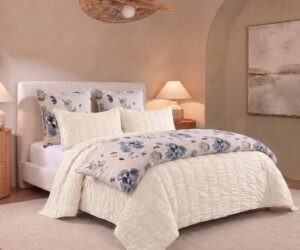 White quilted bed with floral pillows two bedside lamps and beige walls