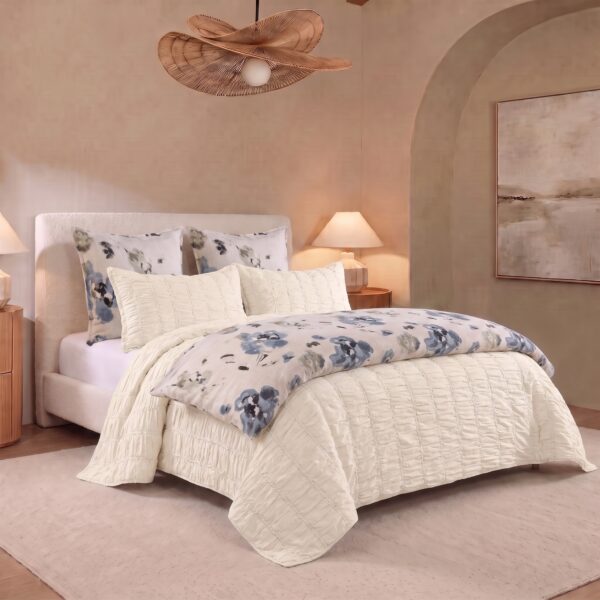 White quilted bed with floral pillows two bedside lamps and beige walls