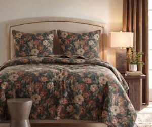 Bedroom with floral bedding on a tufted headboard a nightstand and plant by the window warm lighting creates a cozy feel