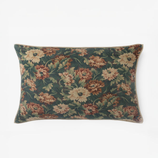 Decorative throw pillow with a dense vintage floral pattern on a dark green background set against a white backdrop at the bottom of the frame