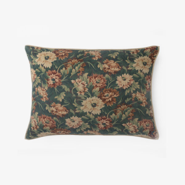 Decorative throw pillow with a dark teal background and pink tan floral pattern photographed on a white backdrop