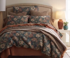 Bed with floral blue green pillows and brown throw lamp on nightstand soft warm lighting in a cozy bedroom