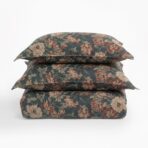 Three floral patterned cushions stacked on a white surface for display