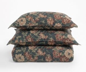 Three floral patterned cushions stacked on a white surface for display