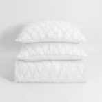 Stack of three white quilted pillows arranged in a vertical stack against a plain light background
