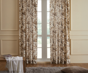 Beige living room with leaf pattern curtains over french doors a gray shag rug a brown floor pillow and a small table draped with a white throw blanket