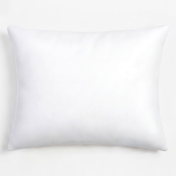 Close up of a soft white pillow with a rounded edge on a pale surface