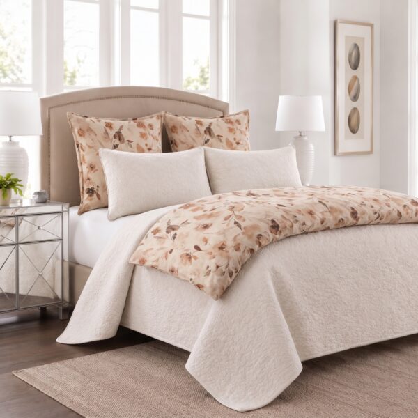 Neutral bedroom with a tufted beige headboard floral patterned pillows and a cream quilt in a bright space with mirrored nightstands and lamps on either side of the bed
