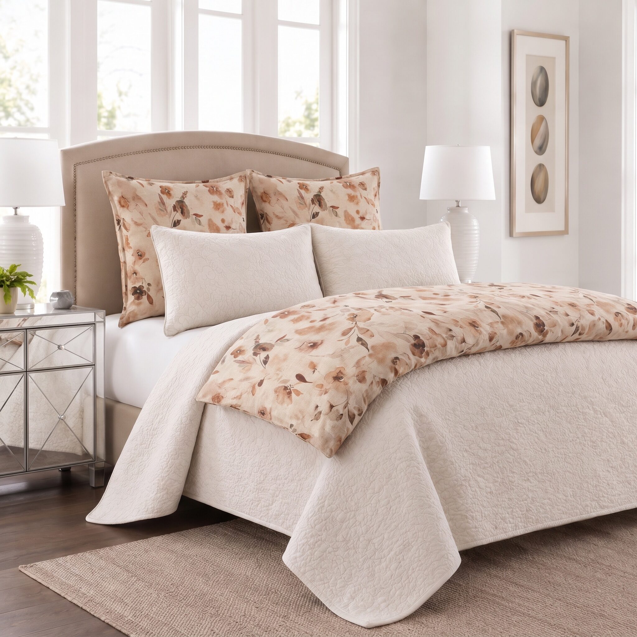 Rosalie Bed Pouf | Amity Home Neutral bedroom with a tufted beige headboard floral patterned pillows and a cream quilt in a bright space with mirrored nightstands and lamps on either side of the bed