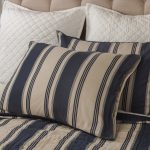 Amity home camden quilt   blue and beige striped quilt with visible hand stitching styled on a bed with matching pillows