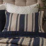 Amity home camden quilt   blue and natural striped quilt with visible hand quilting styled on a bed with a matching pillow