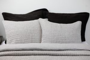 Amity home catalina linen quilt   grey chambray with textured pattern styled on a bed with matching pillows