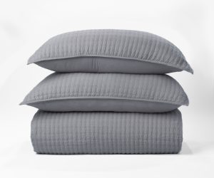 Amity home catalina linen quilt and two matching pillows in neutral grey stacked showing a subtle quilted diamond pattern