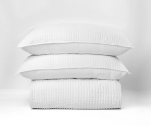 Amity home catalina linen quilt   white linen quilt and two pillows stacked showing crinkled texture and vertical stitching