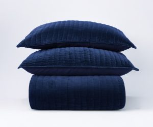 Amity home ethan quilt in indigo blue folded with two matching channel quilted pillows stacked on top showcasing soft texture