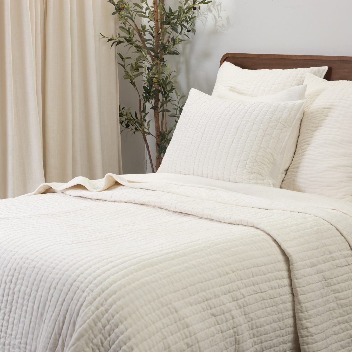 Amity home ethan quilt in ivory featuring a soft textured linear stitch pattern styled on a bed with matching pillows
