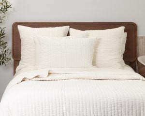 Amity home ethan quilt ivory styled on a bed with a wood headboard featuring a soft subtly crinkled quilted texture