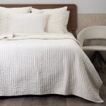 Amity home ethan quilt in ivory featuring soft plush vertical channel quilting styled on a bed with matching shams