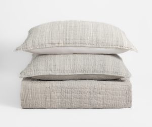 Amity home luce quilt   stack of light greige quilted bedding with subtle stripes and soft texture including two pillows and a folded quilt