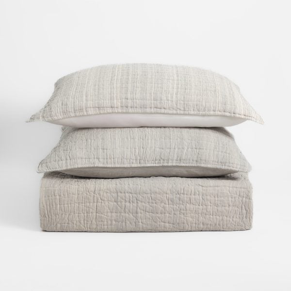 Amity Home Luce Quilt - Stack of light greige quilted bedding with subtle stripes and soft texture, including two pillows and a folded quilt.