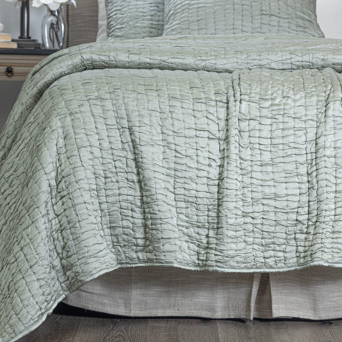 Amity home hadon quilt in seaglass with a luxurious puckered grid texture draped over a bed